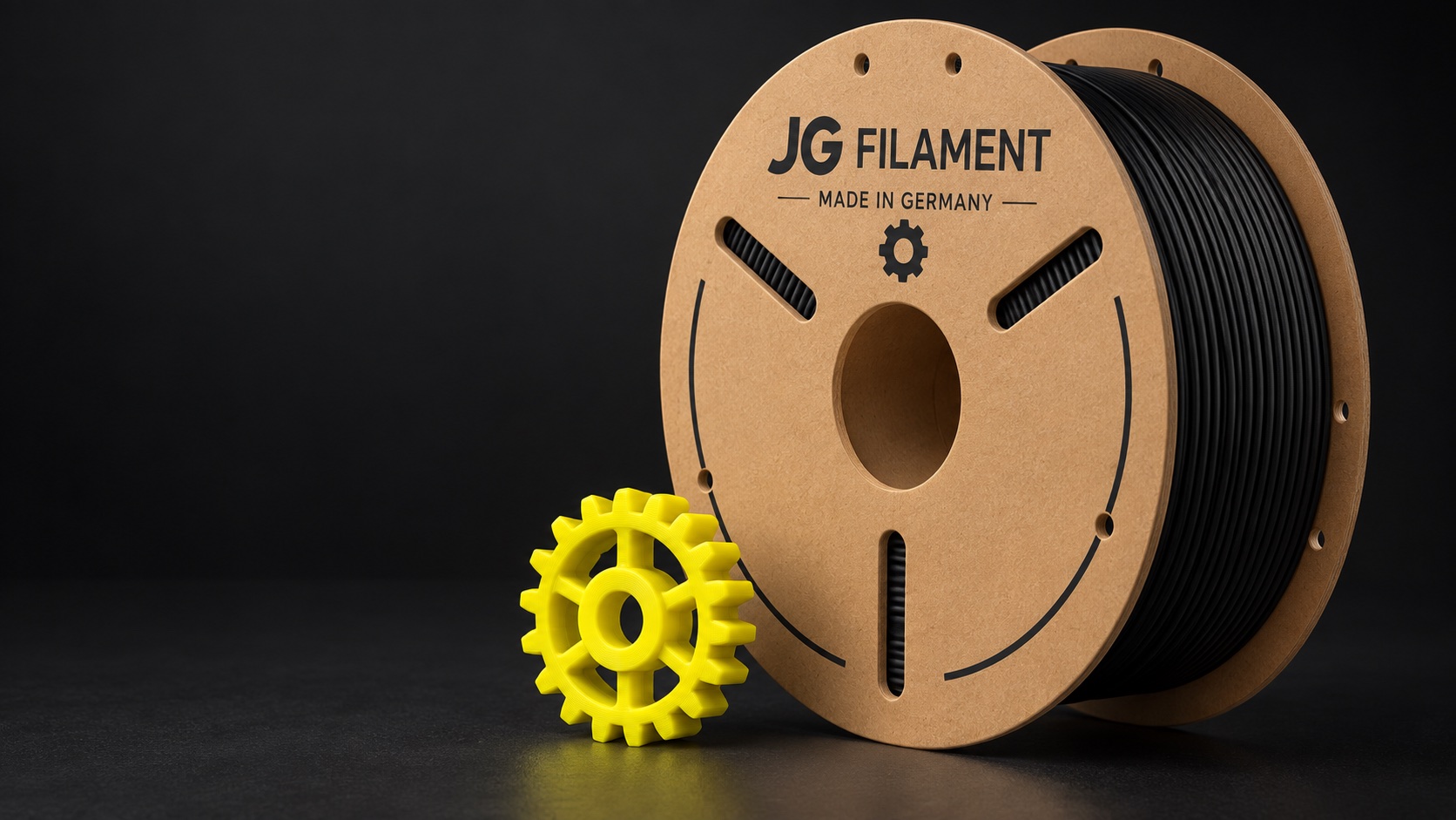 Illustration einer JG-Filament-Pappspule mit dunklem Filament und gedrucktem Zahnrad